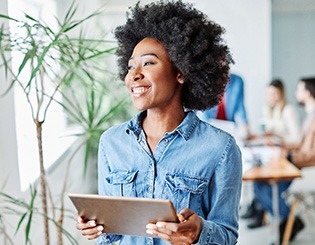 Woman smiling while holding tablet in office