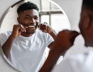 Man smiling while flossing his teeth
