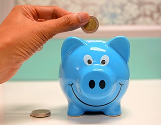 Hand putting coin in piggy bank