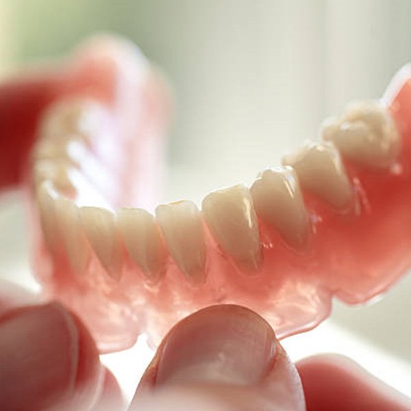 Lower denture held in fingertips