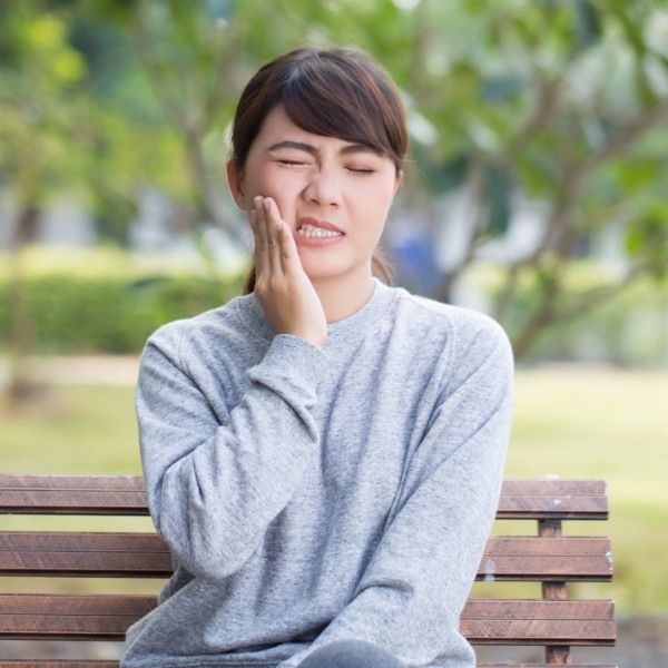 Woman in need of emergency dentistry holding cheek in pain