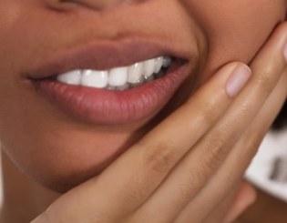 Closeup of patient with toothache holding cheek