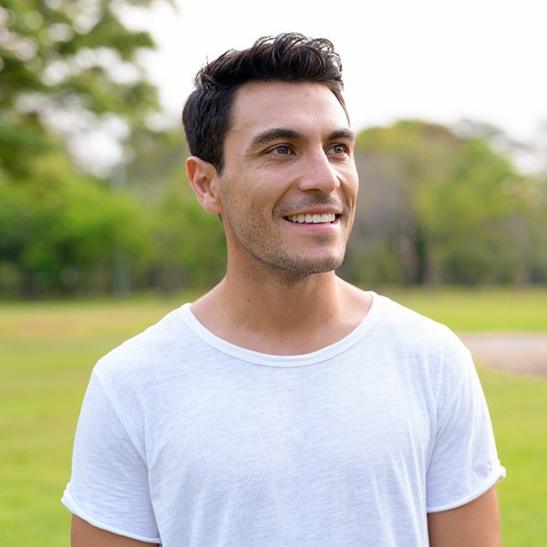 Man in white shirt smiling while outside