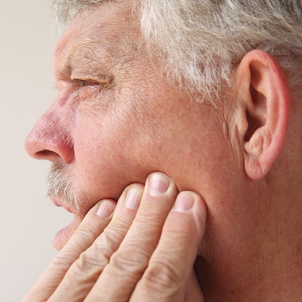Close-up of man rubbing his jaw viewed from side