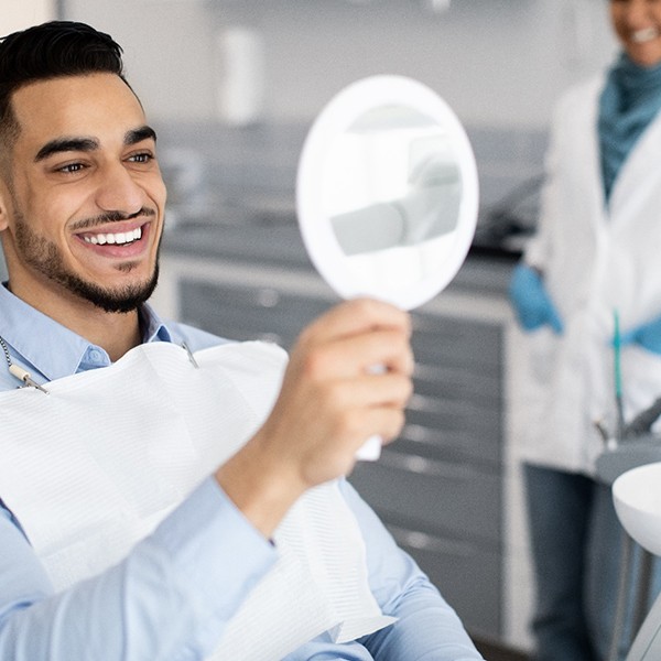 Patient smiling at reflection in handheld mirror