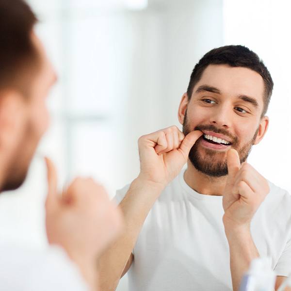 Man flossing his teeth in the bathroom